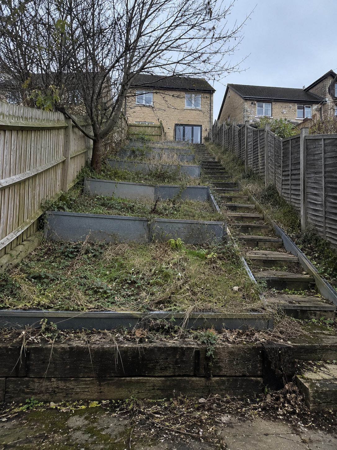 Before: a steep, overgrown garden slope with old metal terracing awaiting transformation